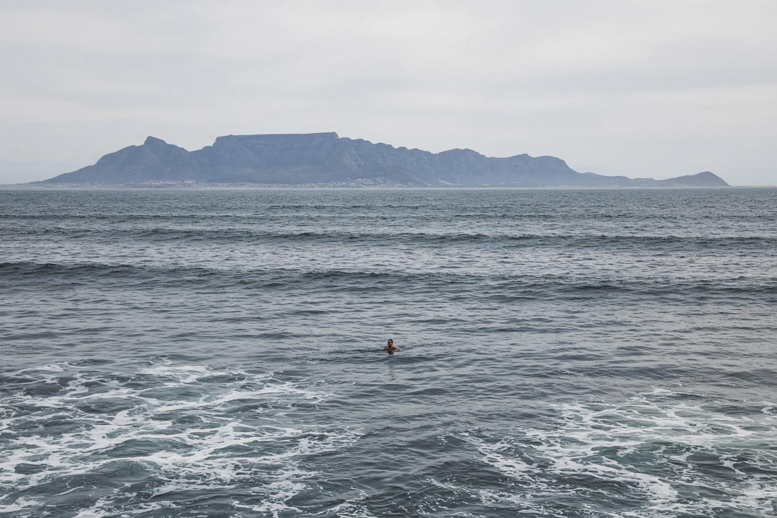 Cold grey Atlantic with Table Mountain across the bay and one tiny distant swimmer
